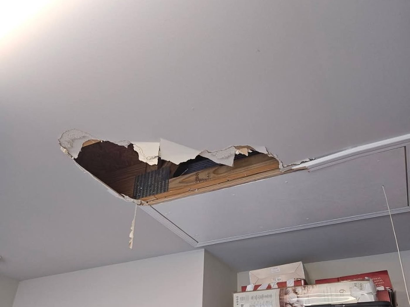 Before the drywall repair: the ceiling torn open with broken drywall hanging and the joists exposed.