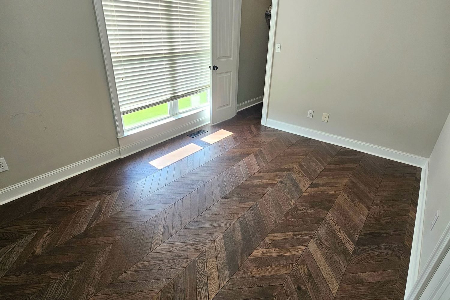 Flooring installation: bedroom with new dark herringbone plank flooring.