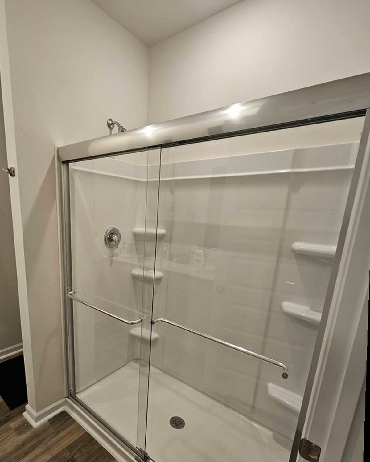 Shower door installation: the shower with new sliding glass doors installed in a polished silver frame.