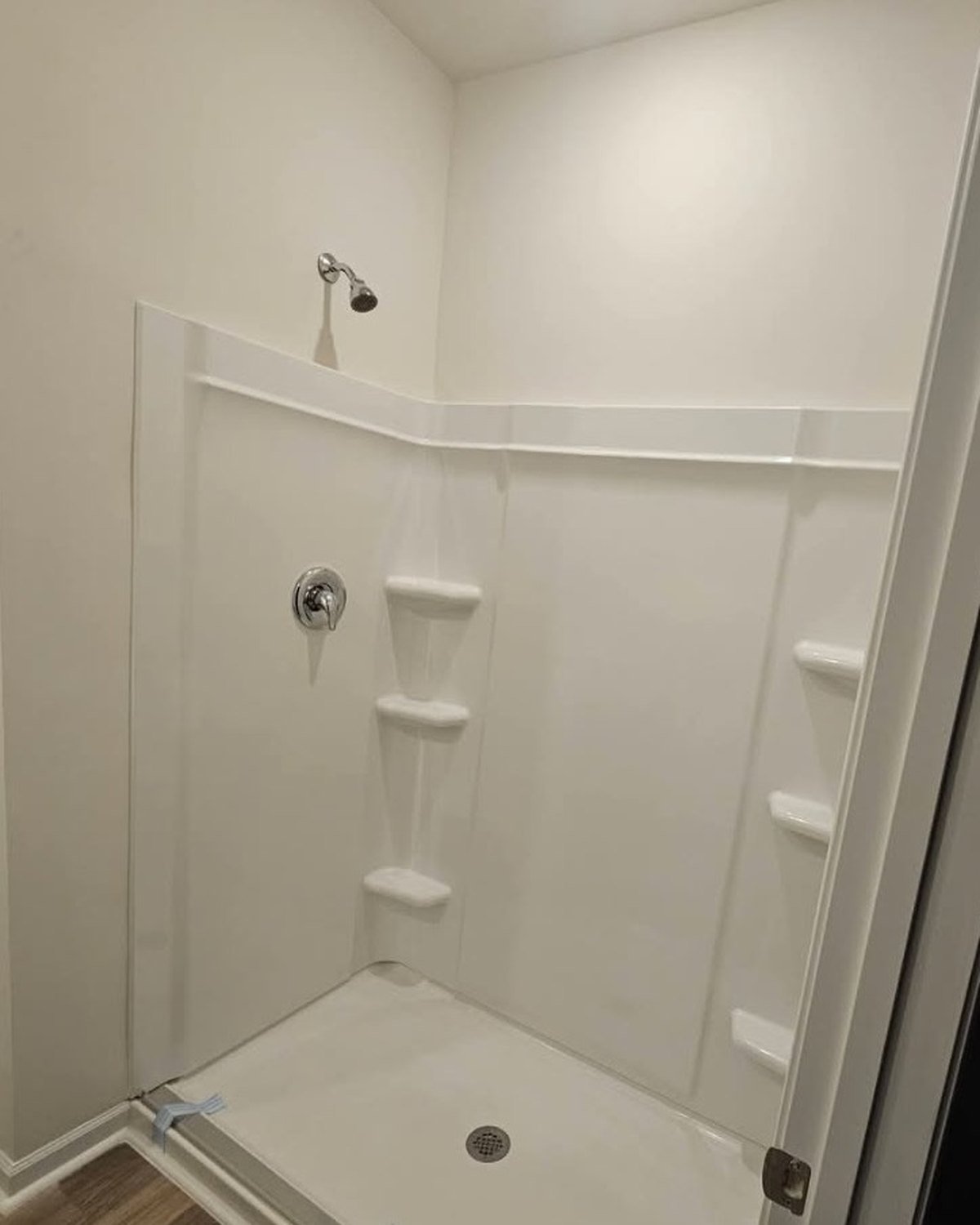 Before the shower door installation: an open stall with no doors and the pan still taped off.